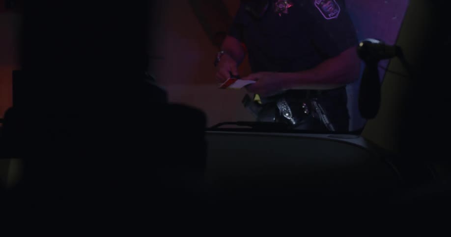 Police officer standing outside a vehicle writing a ticket