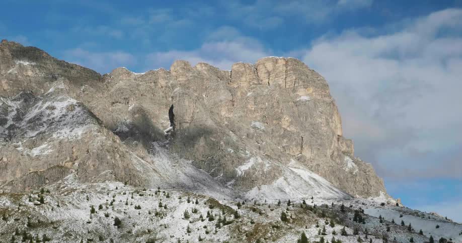 Sparse clouds hang over a stone mountain