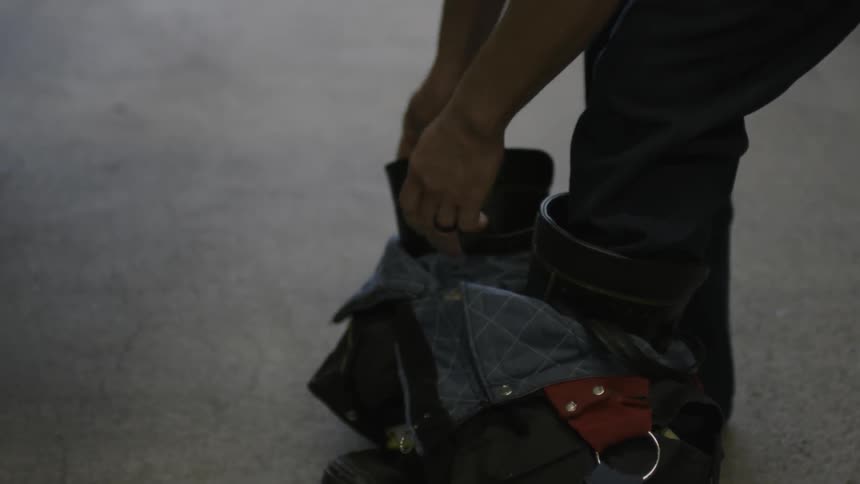 A person placing boots on their feet inside a building