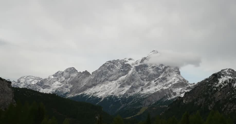 A large mountain with snow and  low lying clouds