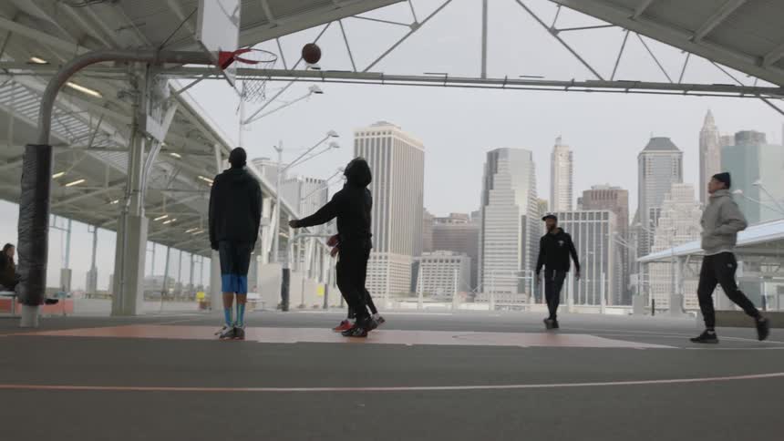 A group of men play basketball on an urban court during the day