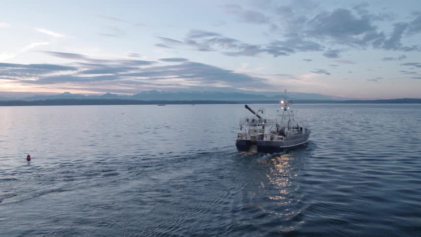 Commercial fishing boat heading out to sea at dusk