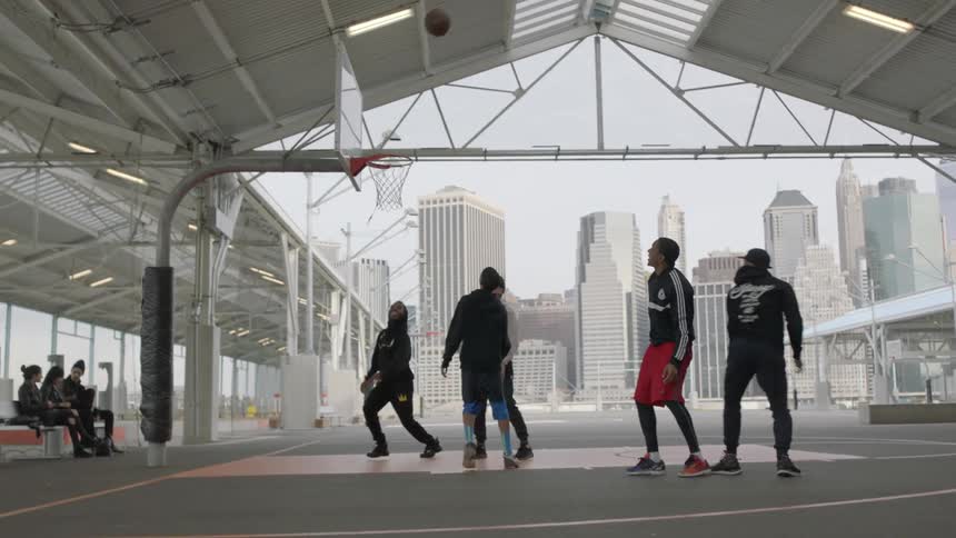 A group of men play basketball on an urban court during the day