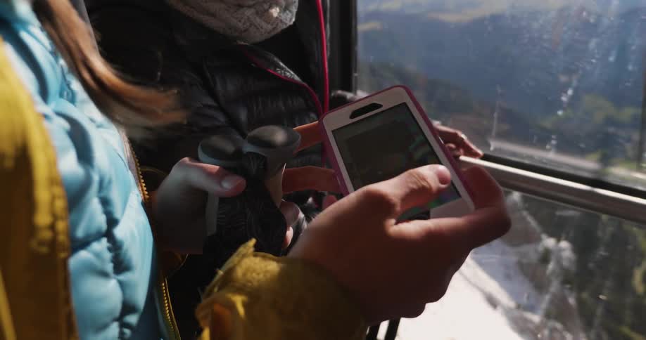 Two women look at a phone on a ski lift