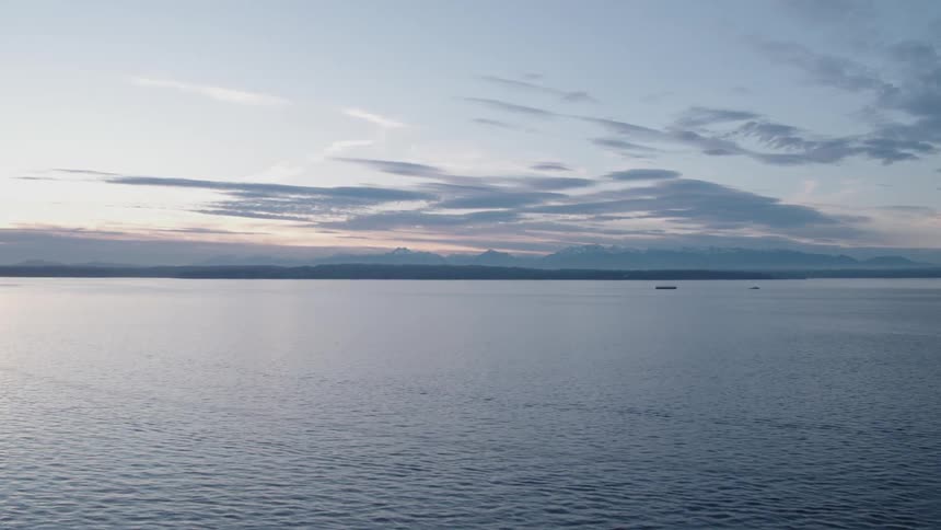 A calm inland bay at sunset with mountains in the distance