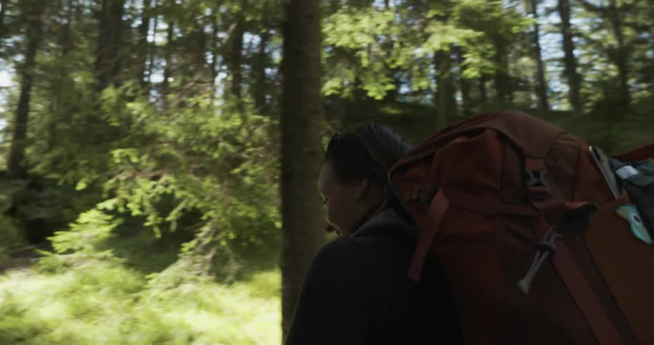 A woman walking with a backpack through a woods