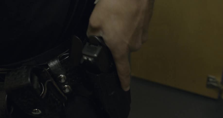 Man wearing a holster puts a gun in it