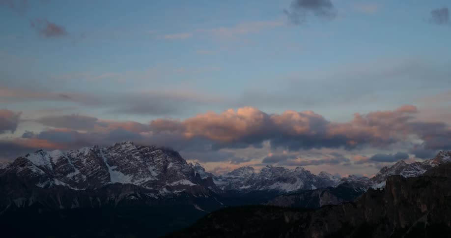 Clouds pass above a snowy mountain