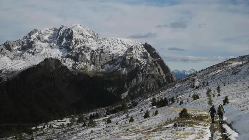 Couple walking on a trail on a snowy mountainside