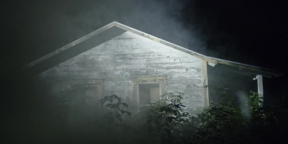 Light filters over a wood building at night