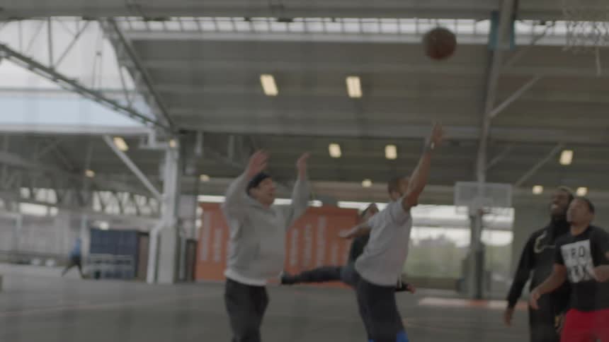 A group of men play basketball on an urban court during the day