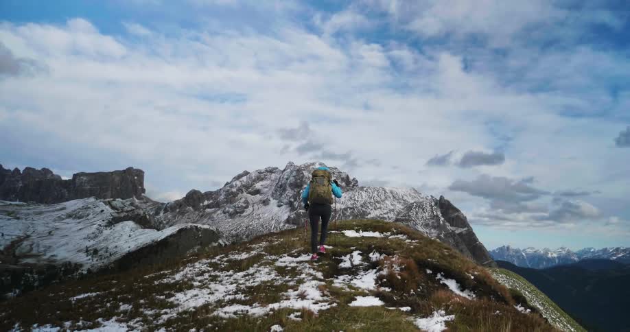Person hiking up a snowy mountain using walking sticks