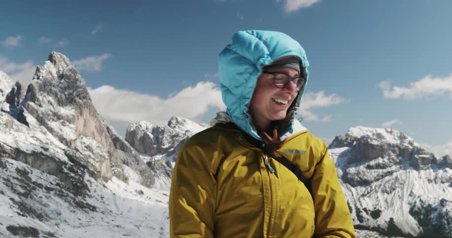 Smiling woman standing near snowy mountains looks around
