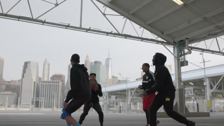 A group of men play basketball on an urban court during the day