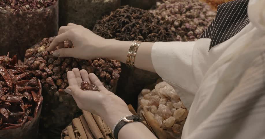 A woman is picking up spices in a market