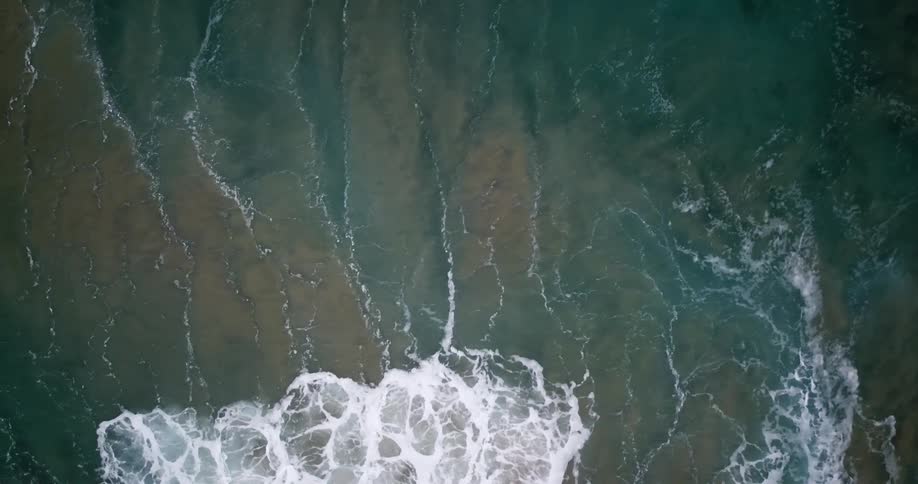 A wave crests and crashes as it rolls toward a shore