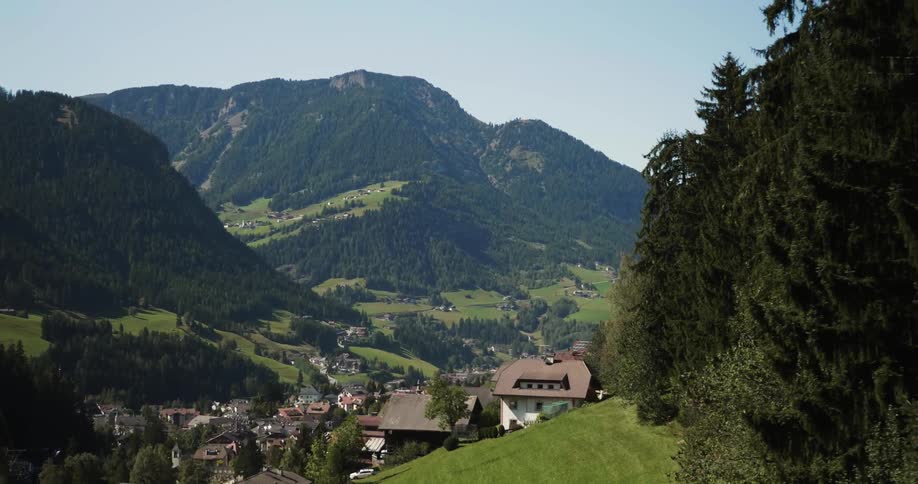 Village of houses in between tree covered mountains