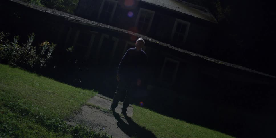 Person standing outside in front of a house at night