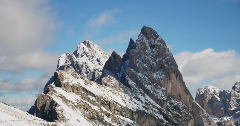 A large rock with snow as the clouds pass overhead leaving a slight shadow