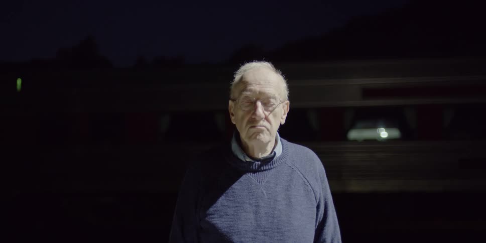 A light shines on a man standing in front of a train at night