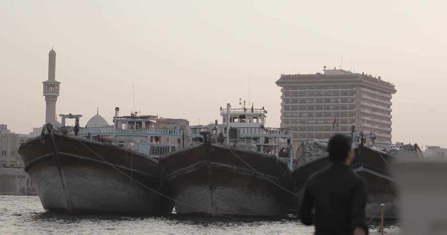 A man walks along the pier with three big boats docked