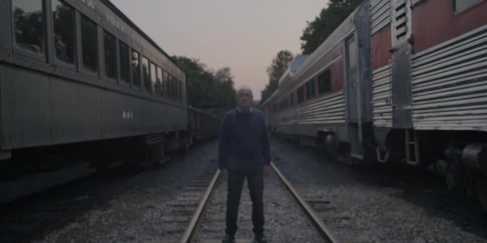 A man stands on tracks in between two trains