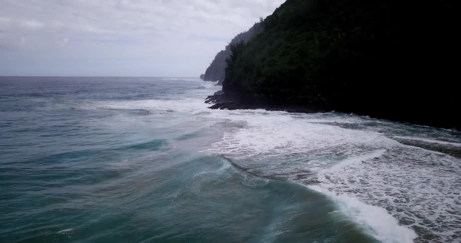 Waves roll onto the shore at the base of cliffs