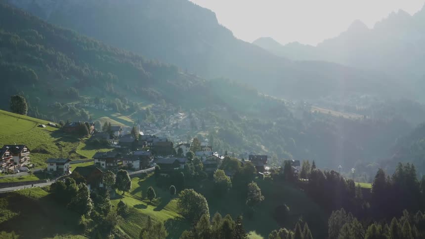 Haze drifts over a village in a mountain valley during the day