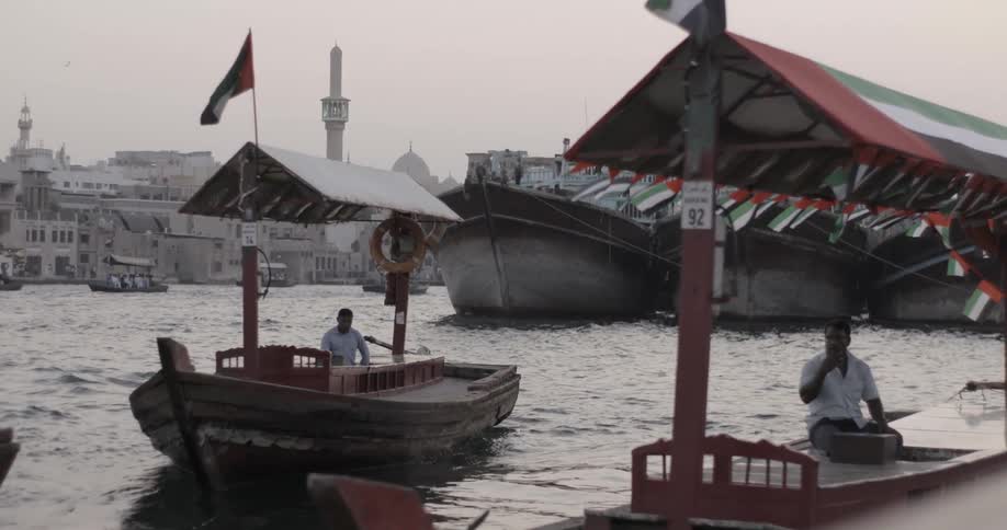 A man pulls an empty tourist boat out of a dock in a foreign harbor