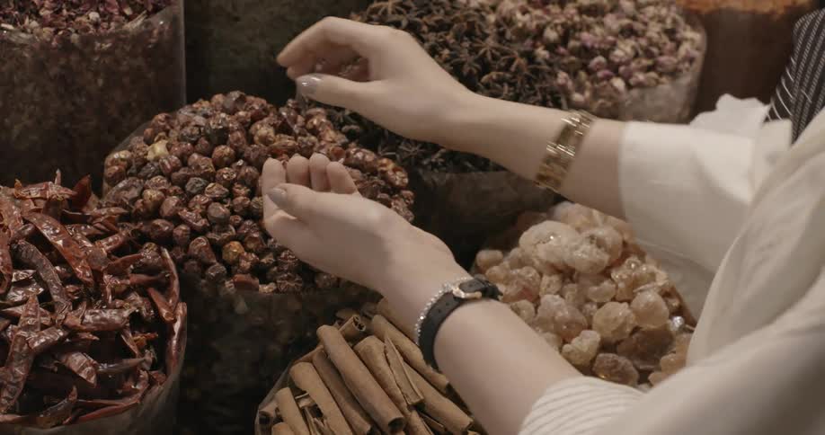 A woman is picking up spices in a market