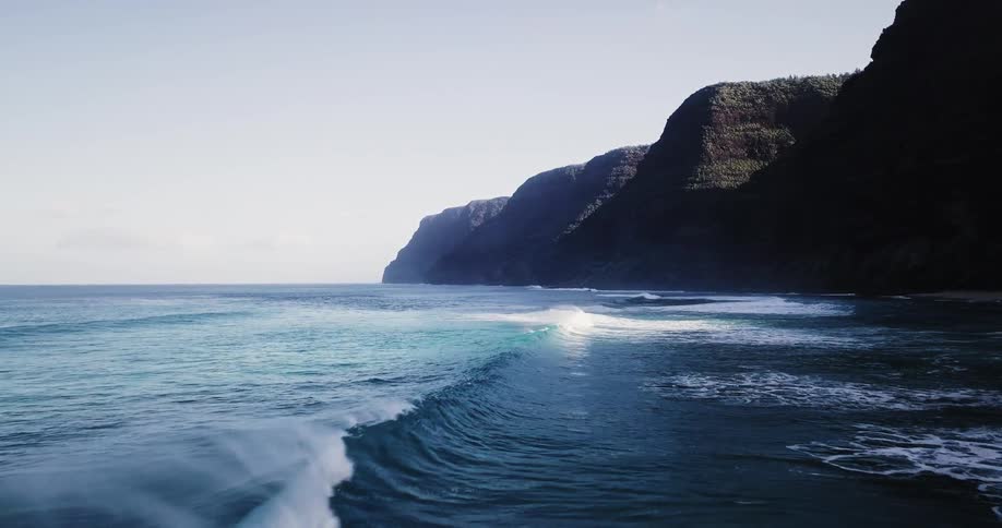 Waves roll toward the cliffs of a shoreline on a sunny day
