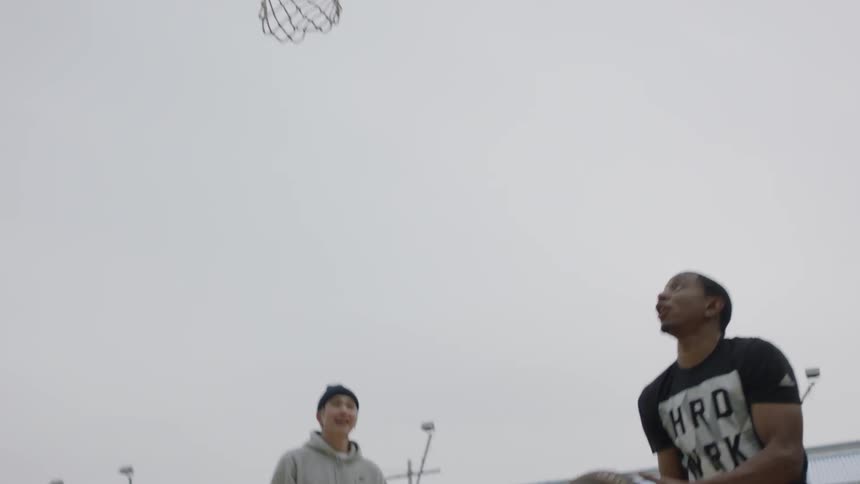 A group of men play basketball on an urban court during the day