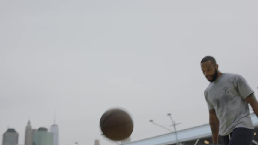 A group of men play basketball on an urban court during the day
