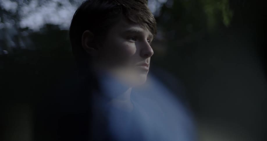 A young male is outdoors staring into the distance