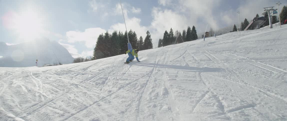 Person snowboards down a steep hill on a sunny day