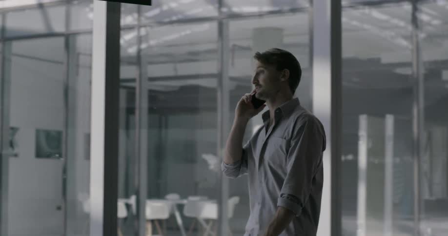 Man talking on a phone walks through an office building