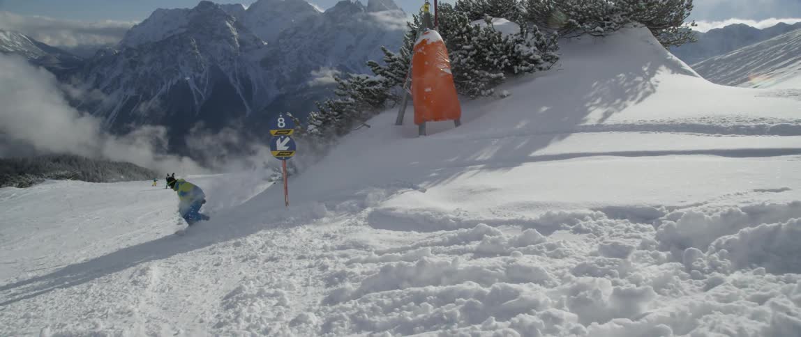 Person snowboarding and jumping over a small slope