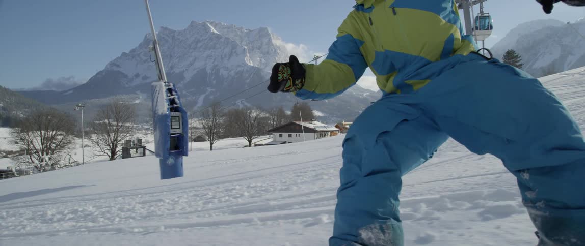 A snowboarder rides down a mountain near a ski lift during the day
