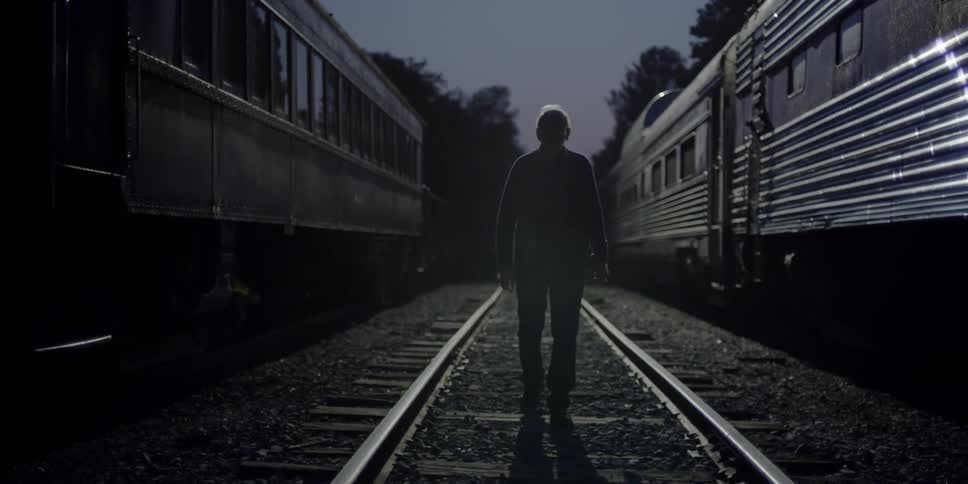 Man walks down train tracks in between two stopped trains at night