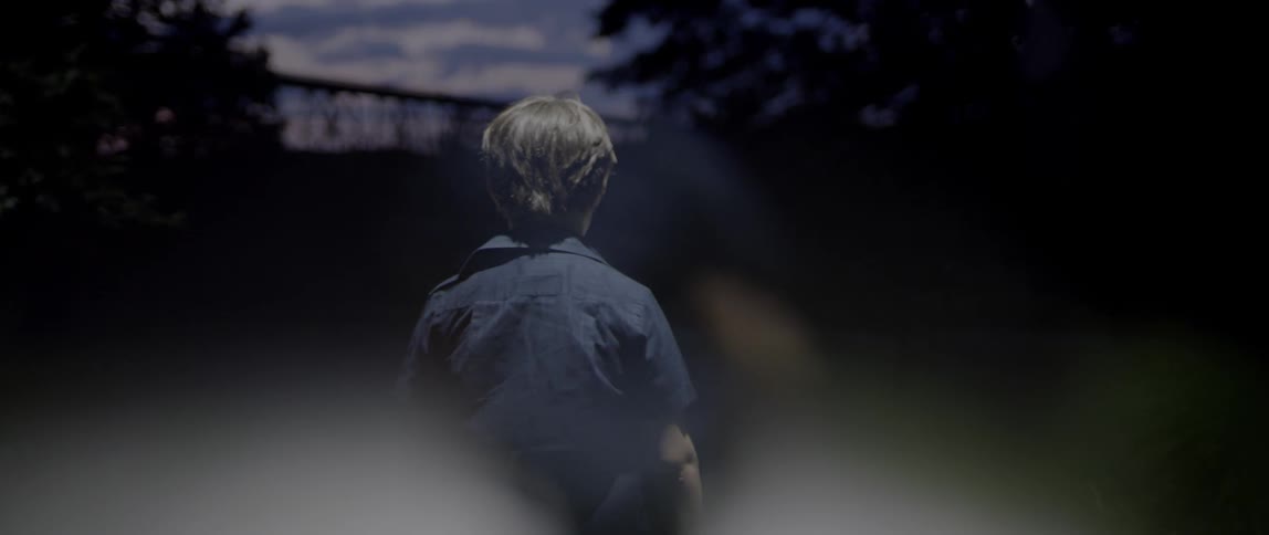 A young boy walks outside at dusk