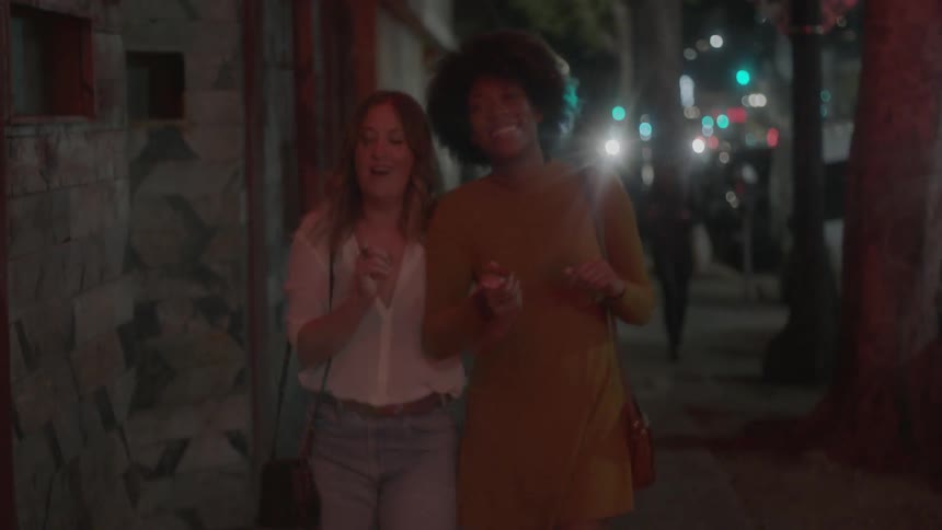 Women walk down the city sidewalk at night