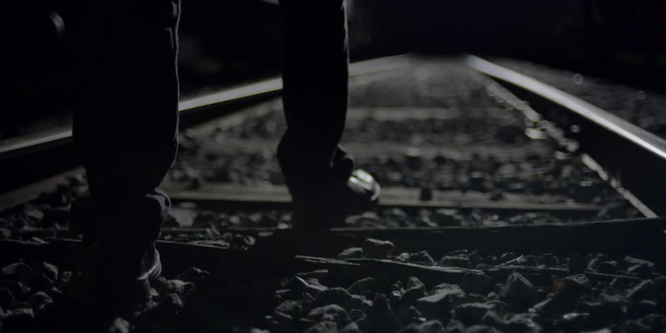 A person is walking on train tracks at night