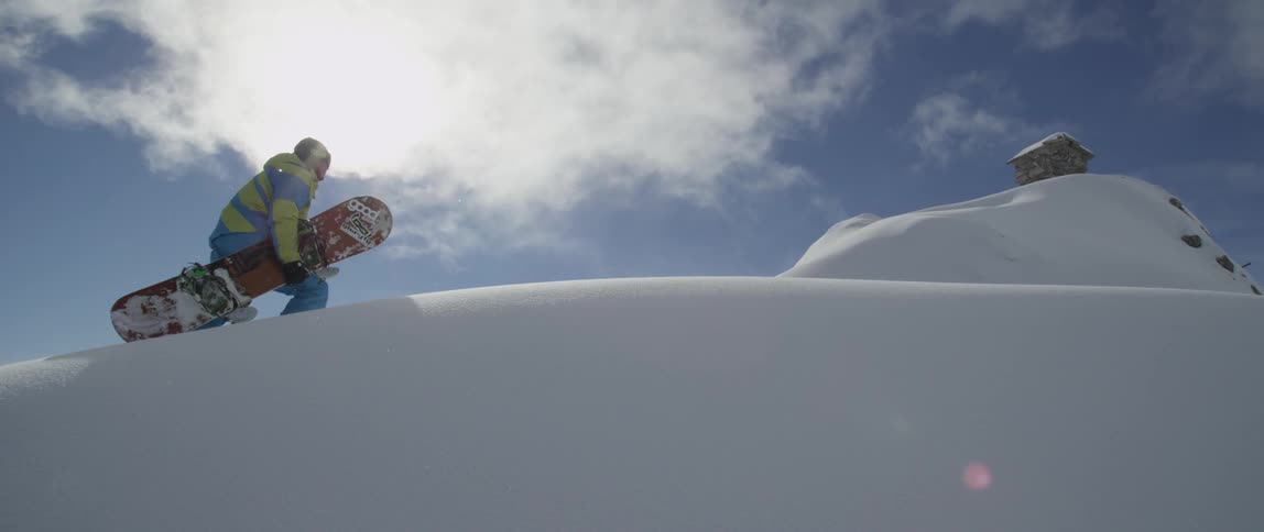 Man carrying snowboard walks up a hill