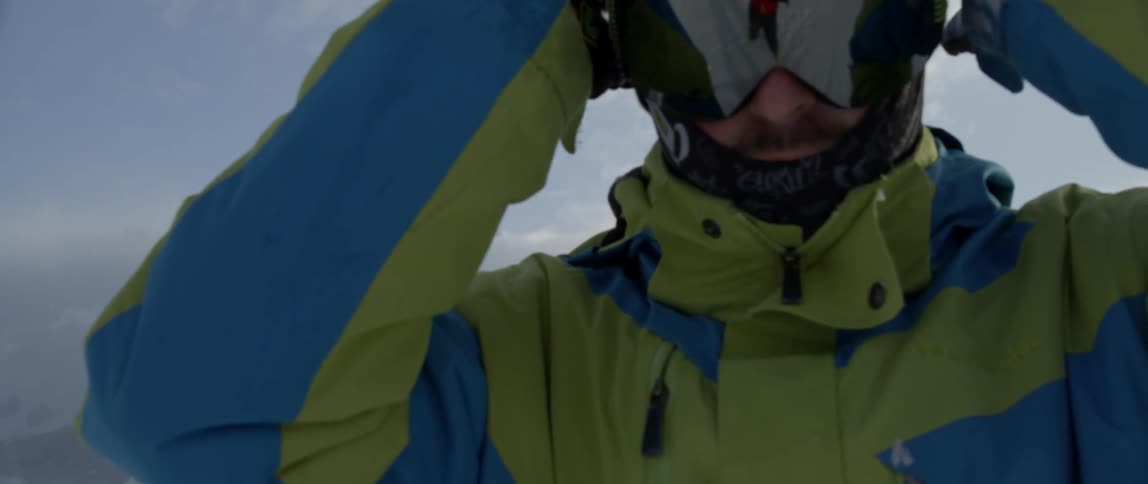 Man standing outside in winter pulls goggles over his face