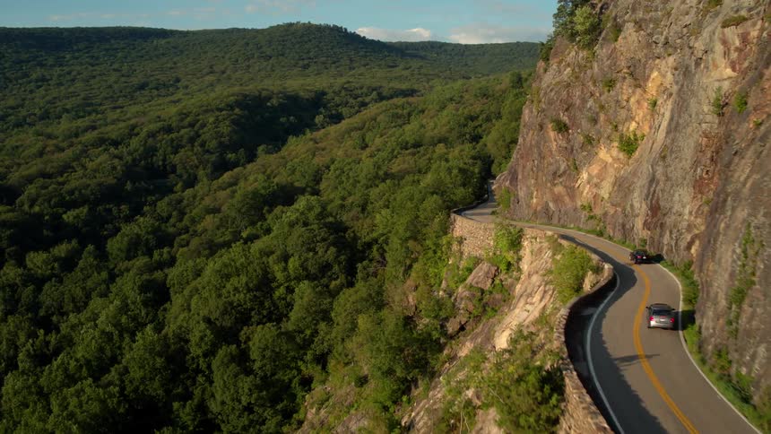 Cars travel on a road winding around a cliff