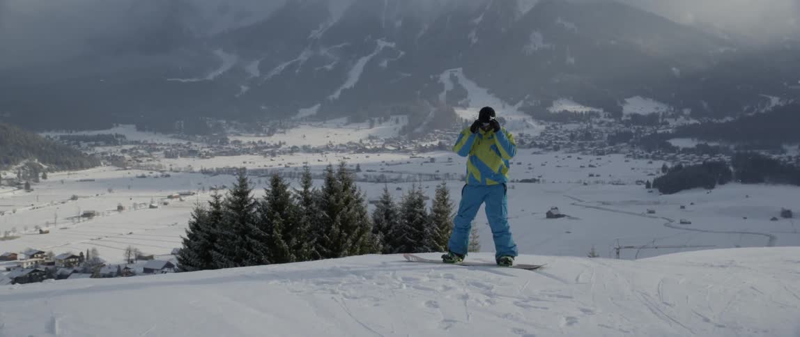 Person standing on a snowboard looks out at the scenery