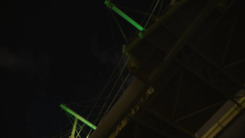 People stand on a platform on a bridge at night
