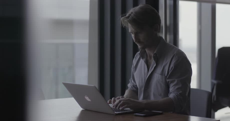 Man sits at a desk working on a laptop