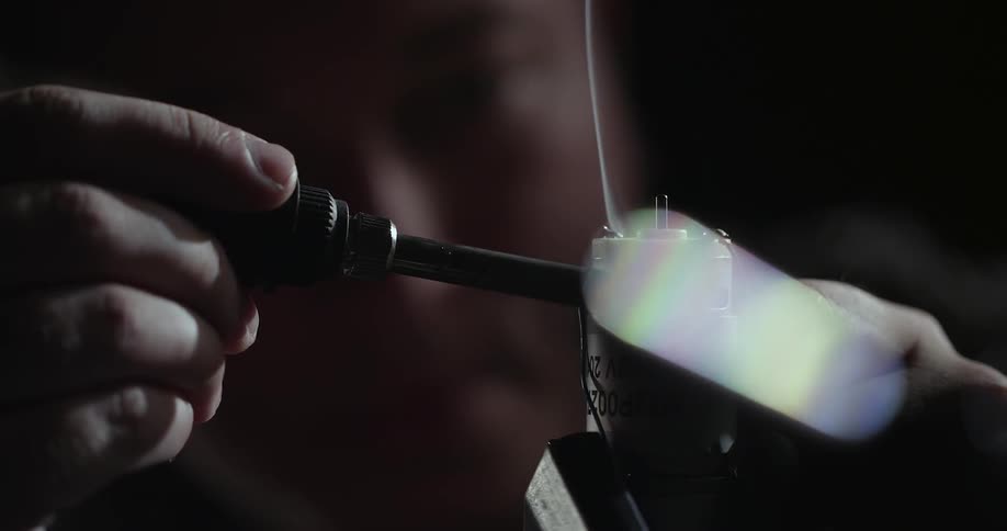 Smoke rises as a man uses a soldering iron