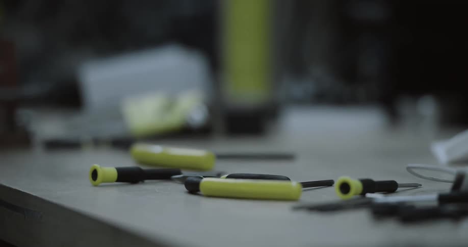 A group of tools laying on a table and a person grabs one of them